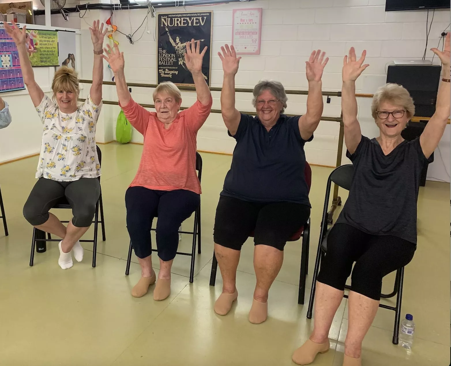 Seated dance class participants with arms raised